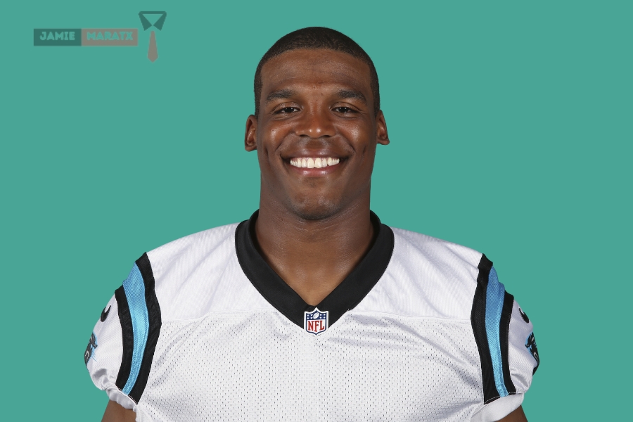 Cam Newton is smiling in his Carolina Panthers jersey, representing his successful NFL career and $75M net worth, discussed in the blog post "Cam Newton Net Worth."