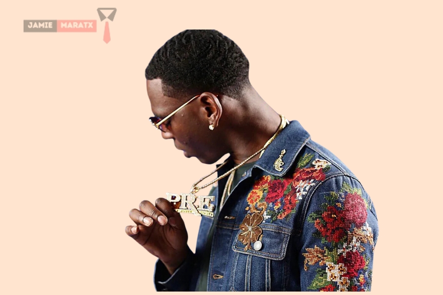 Young Dolph wearing a floral denim jacket and showcasing his PRE chain, symbolizing his independent record label, for the blog post "Young Dolph Net Worth."