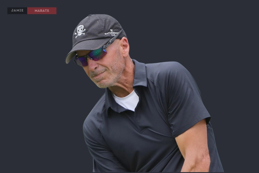 Rocco Mediate wearing a black cap and sunglasses while focusing on a golf shot.