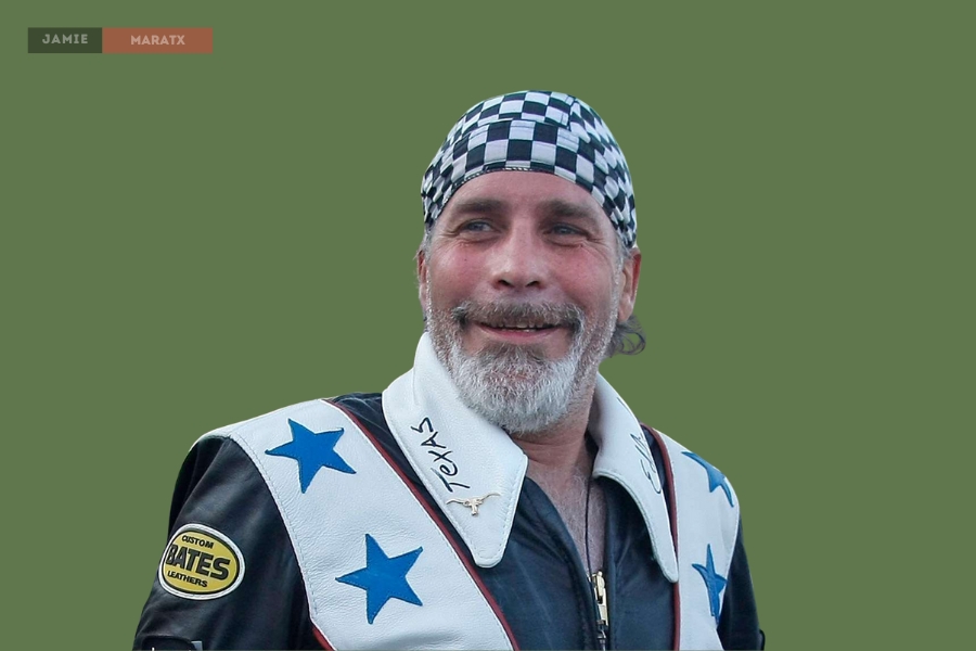 Robbie Knievel wearing a checkered bandana and a custom leather jacket with blue stars, smiling.