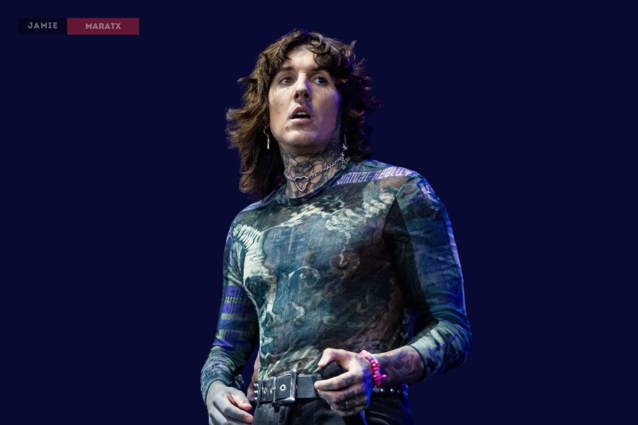 Oli Sykes performing on stage in a patterned shirt, showcasing his tattoos and signature style.