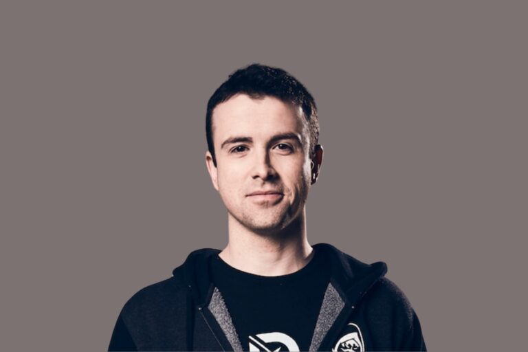 DrLupo wearing a hoodie and smiling in front of a plain gray background.