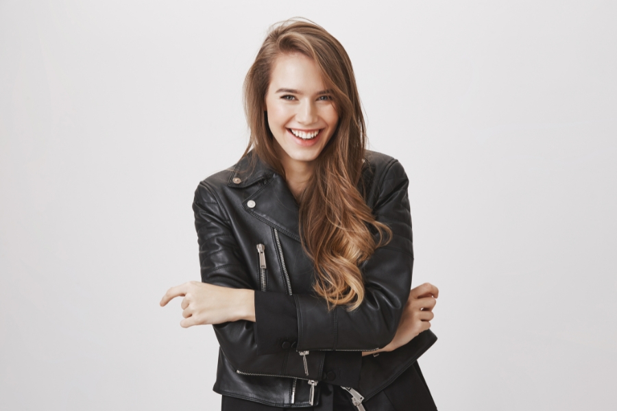 Smiling young woman in a black leather jacket with arms crossed