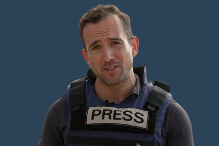 BBC journalist Hugo Bachega reporting in a press vest, representing his distinct accent and global media presence.