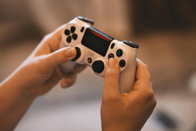 Hands holding a white gaming controller while playing a video game, representing the addictive gameplay experience of Infinite Craft.