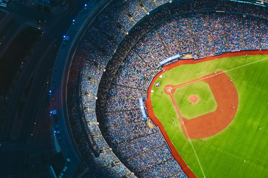 Aerial view of a packed baseball stadium at night with fans watching a live game.