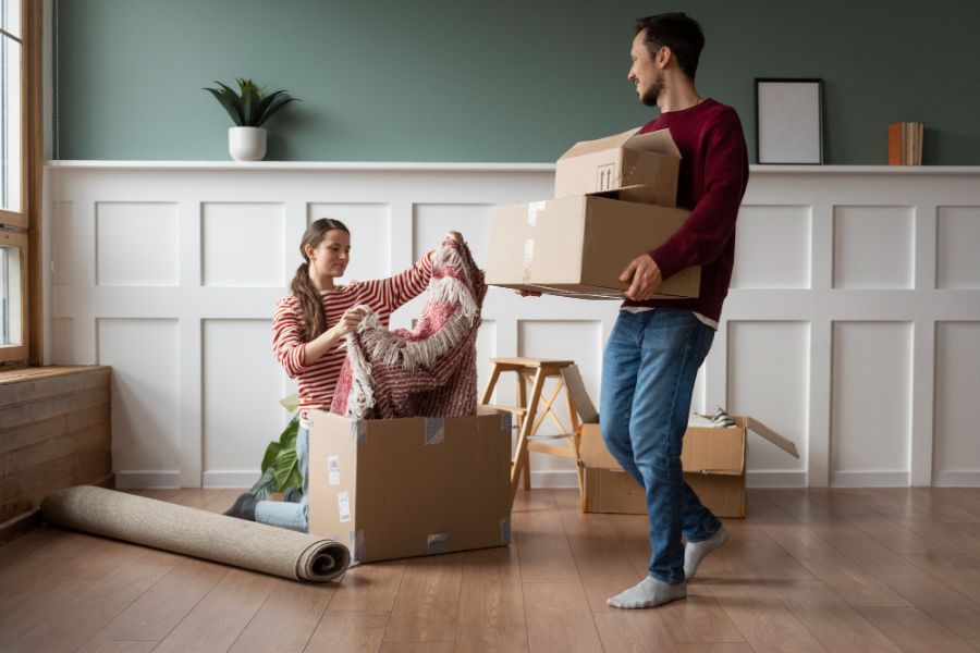 A young couple unpacks boxes in their new home, organizing and setting up during a smooth moving day.